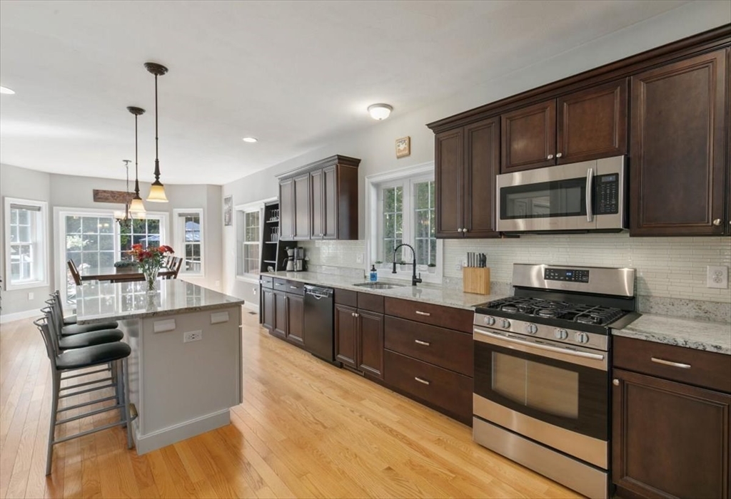 135 Pepperell Road Groton, MA 01450 - Photo 5 of 41 a kitchen with stainless steel appliances wooden cabinets a stove a sink and a microwave