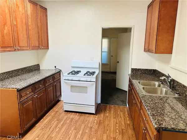 a kitchen with granite countertop a sink stove and cabinets