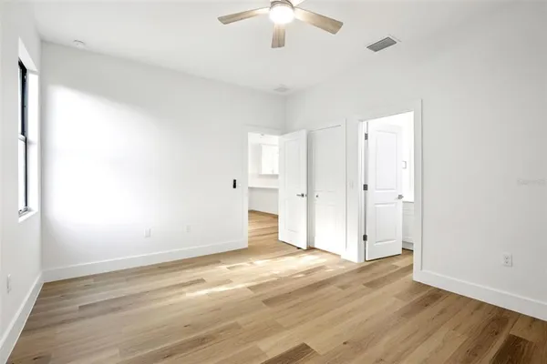 an empty room with wooden floor and a ceiling fan