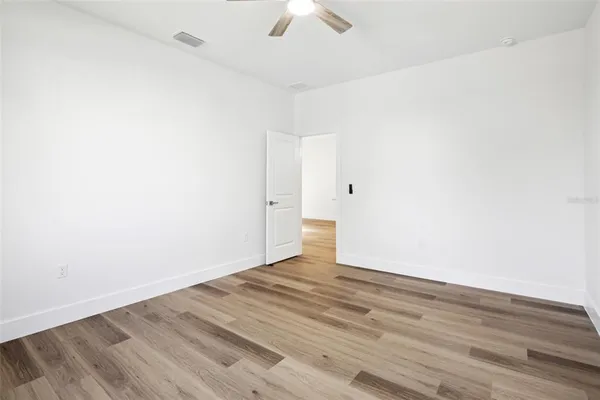 an empty room with wooden floor fan and windows
