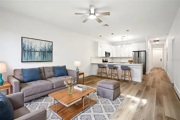 a living room with furniture kitchen view and a chandelier