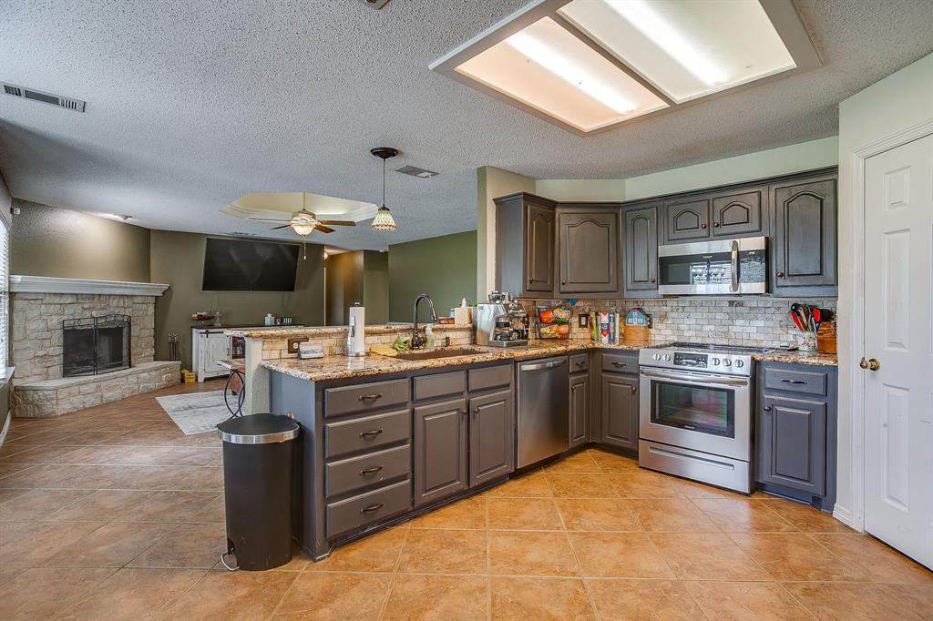 1050 Hampel Road Palmer, TX 75152 - Photo 17 of 35 a kitchen with stainless steel appliances granite countertop a stove top oven a sink dishwasher and a fireplace with wooden floor