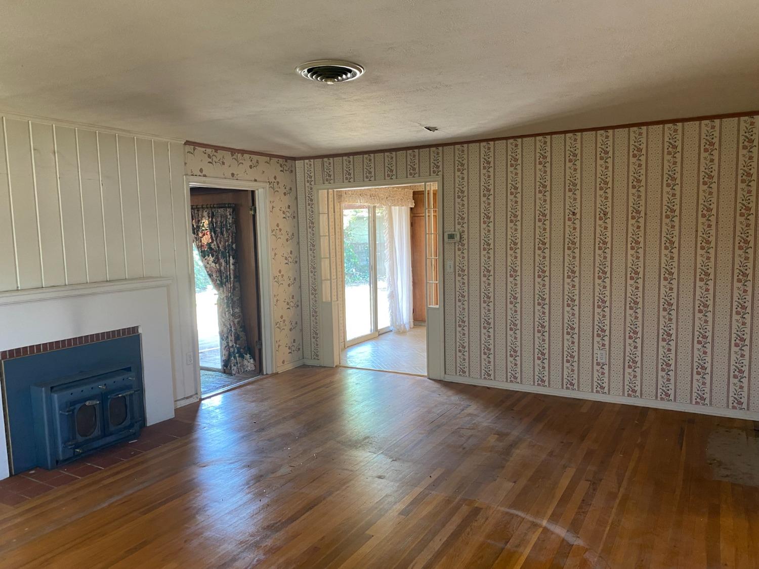 2828 E Street Selma, CA 93662 - Photo 8 of 17 an empty room with wooden floor fireplace and windows