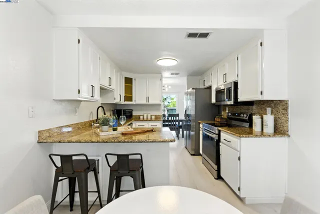 a kitchen with stainless steel appliances granite countertop a table chairs microwave and cabinets