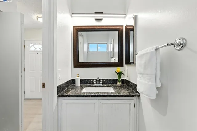 a bathroom with a granite countertop sink a mirror and a vanity