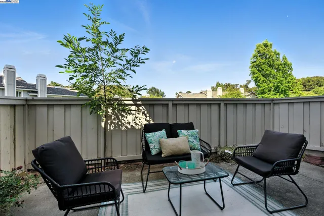 a patio with table and chairs and potted plants with wooden floor and bench