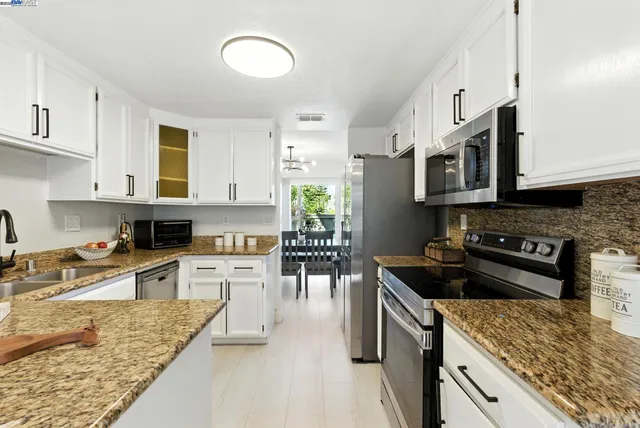 a kitchen with stainless steel appliances granite countertop a stove top oven a sink a counter space and cabinets