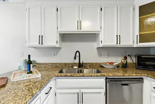 a kitchen with granite countertop a sink stove and cabinets
