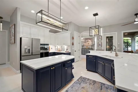 a kitchen with cabinets a counter space stainless steel appliances and a chandelier