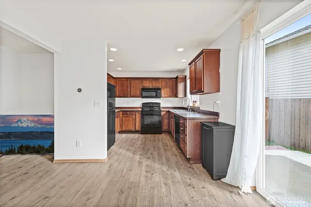 a kitchen with stainless steel appliances granite countertop a refrigerator a sink dishwasher a stove with wooden cabinets and floor