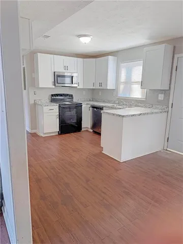 a kitchen with granite countertop a stove top oven a sink and white cabinets