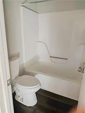 a white toilet sitting next to a bath tub