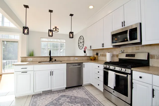 a kitchen with stainless steel appliances granite countertop a sink a stove a microwave and wooden cabinets