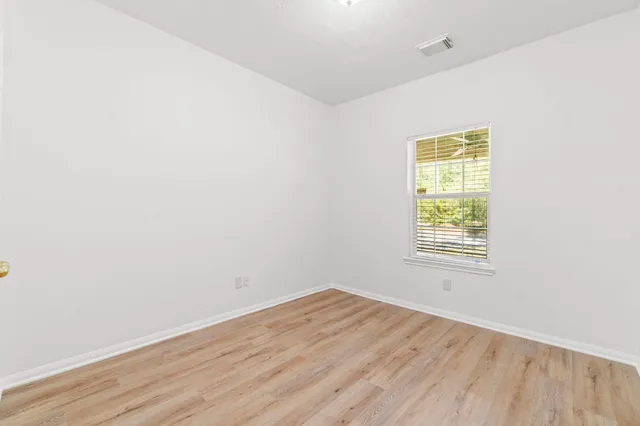 an empty room with wooden floor and a window