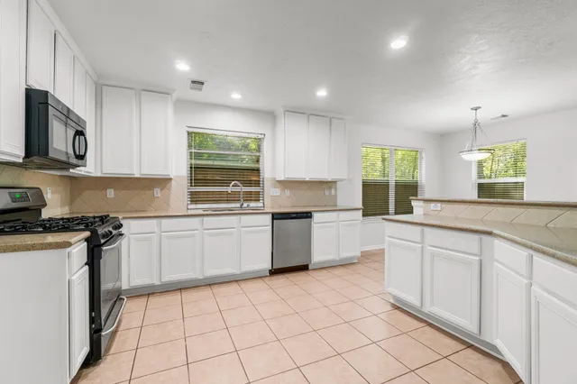 a kitchen with stainless steel appliances granite countertop a stove a sink and a microwave