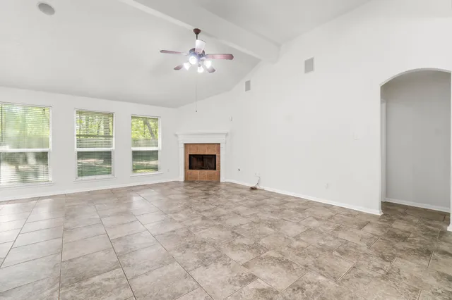 an empty room with windows and fireplace