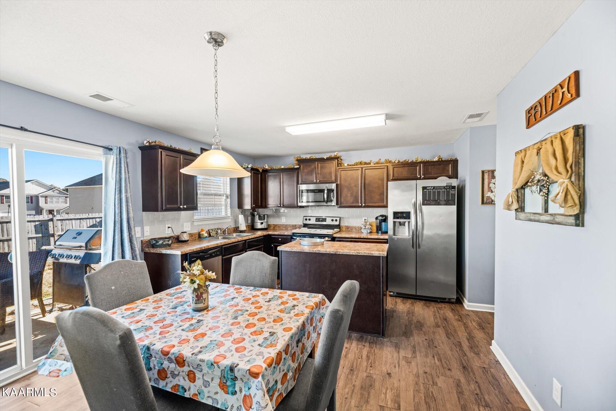 7136 Lawgiver Circle Corryton, TN 37721 - Photo 4 of 12 a kitchen with stainless steel appliances kitchen island granite countertop a refrigerator a stove top oven a dining table and chairs with wooden floor