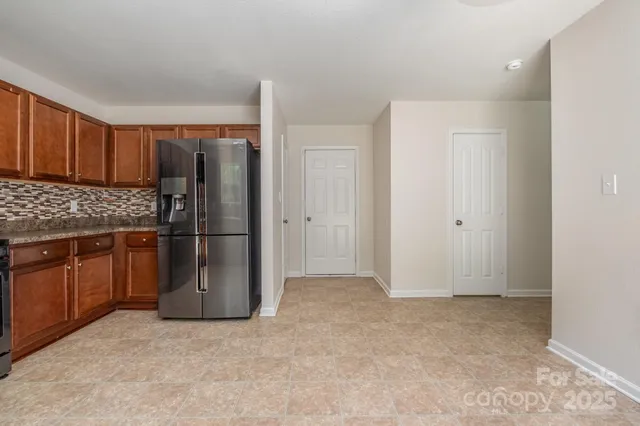 a view of kitchen with refrigerator and wooden cabinets