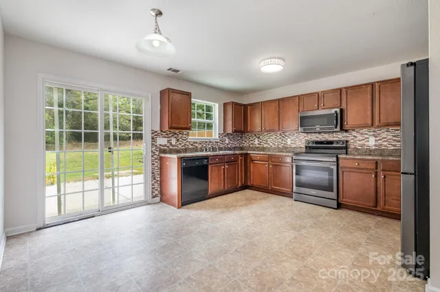 a kitchen with stainless steel appliances granite countertop a stove top oven a sink dishwasher a refrigerator and a fireplace