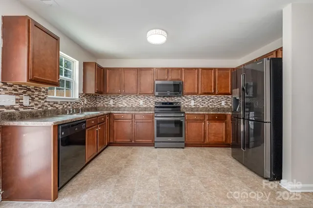 a kitchen with stainless steel appliances granite countertop a stove a sink dishwasher a refrigerator and a microwave oven