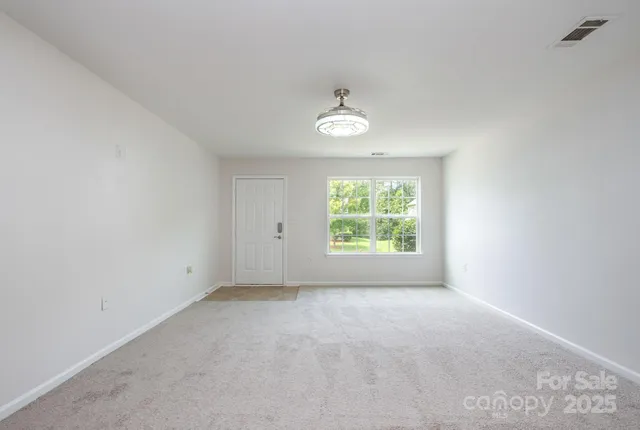 an empty room with windows and ceiling fan