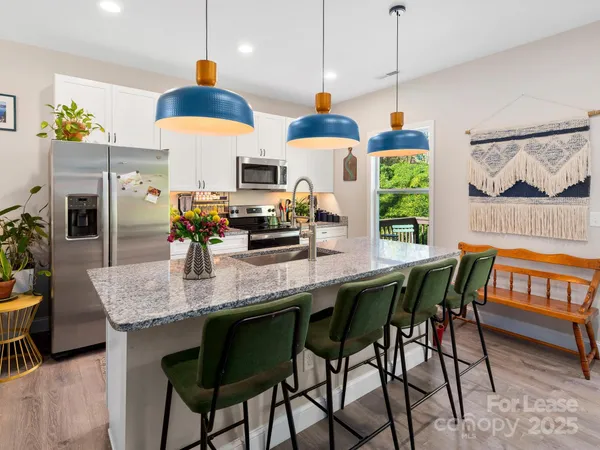 a kitchen with stainless steel appliances granite countertop a stove a kitchen island a dining table and chairs