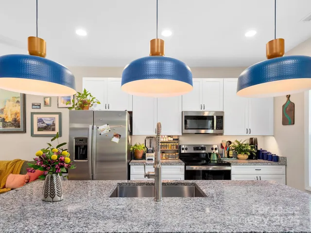 a kitchen with stainless steel appliances granite countertop a sink a stove and a wooden floors