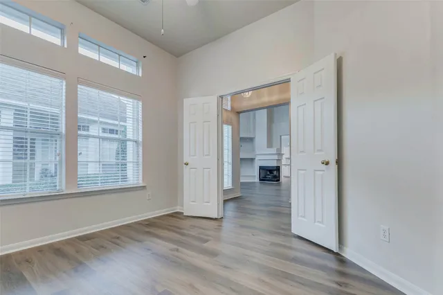a view of an empty room with wooden floor and a window