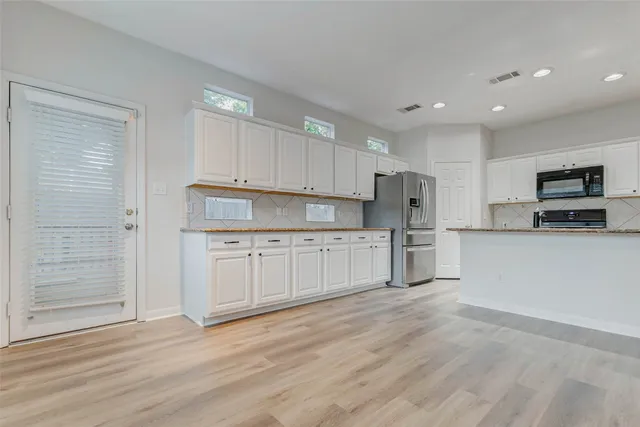 a kitchen with white cabinets and stainless steel appliances