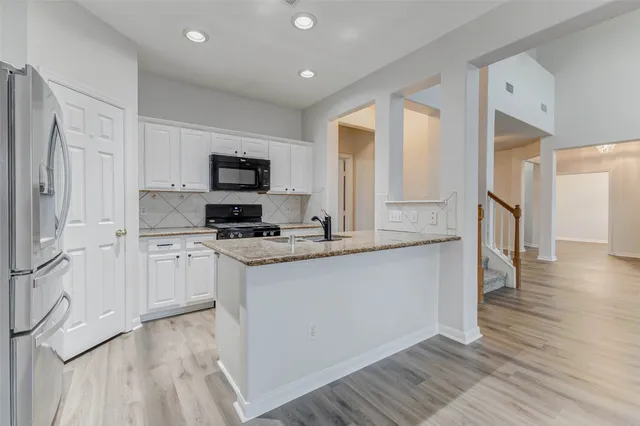 a kitchen with stainless steel appliances granite countertop a stove top oven a sink and a refrigerator