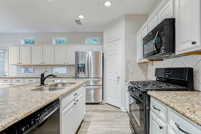 a kitchen with stainless steel appliances granite countertop a sink stove microwave and refrigerator