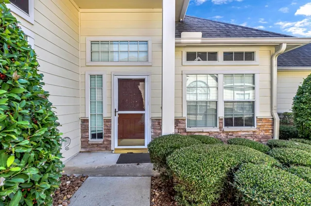 a view of a brick house with large windows and plants