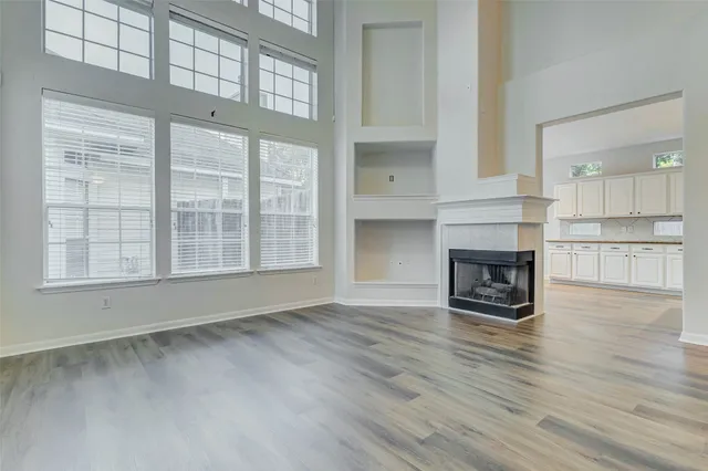 an empty room with wooden floor fireplace and windows