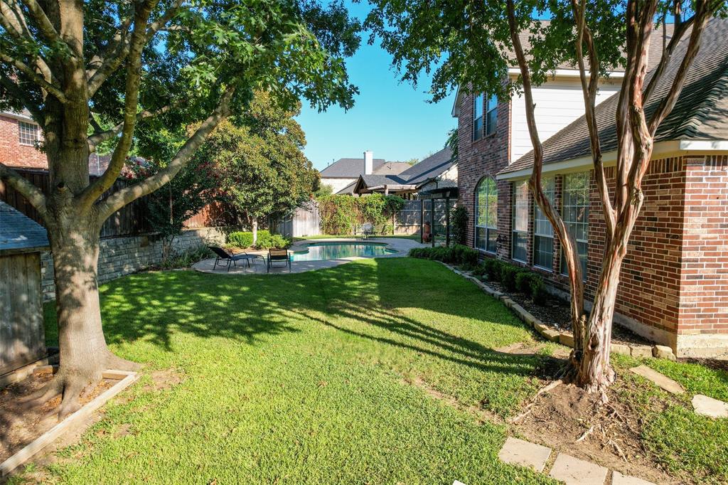 4405 Ridgecove Drive Rowlett, TX 75088 - Photo 31 of 37 Expansive lawn area, brick-clad exterior, established trees, and built-in swimming pool with surrounding hardscaping