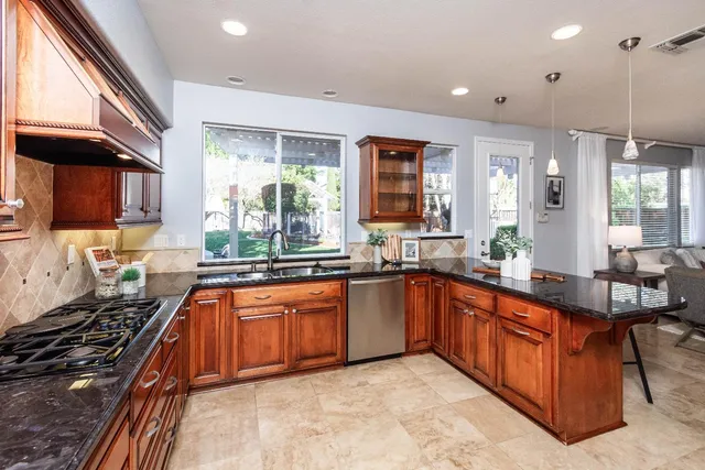 a kitchen with stainless steel appliances granite countertop a refrigerator and a stove top oven