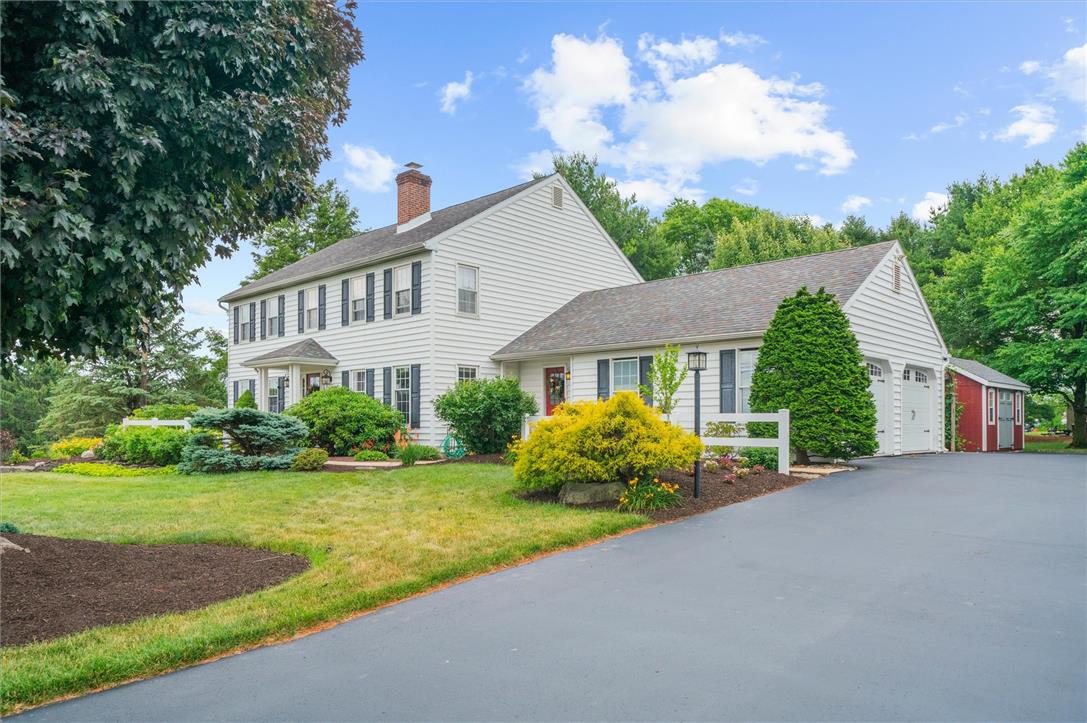 5616 Snowdrift Road Orefield, PA 18069 - Photo 3 of 36 A classic colonial home with vibrant landscaping and a spacious driveway, featuring an attached two-car garage and a charming red shed.