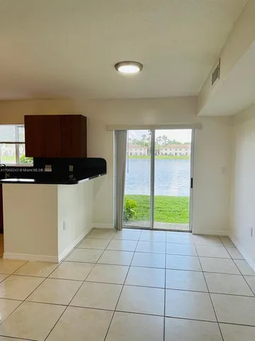 a view of a livingroom with an empty space and a kitchen