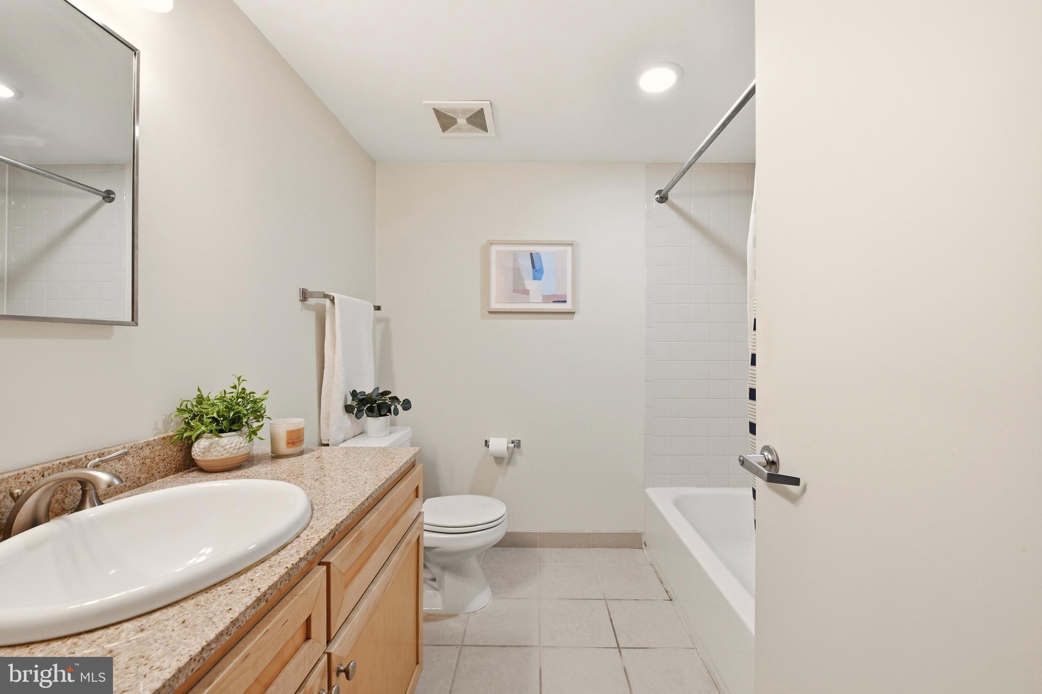 1150 K Street Northwest, Unit 1109 Washington, DC 20005 - Photo 13 of 33 a bathroom with a granite countertop sink a toilet a mirror and bathtub