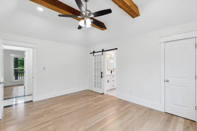 an empty room with wooden floor chandelier fan and windows