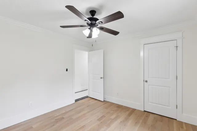 an empty room with wooden floor and ceiling fan