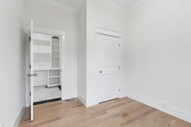 a view of an empty room with wooden floor and closet