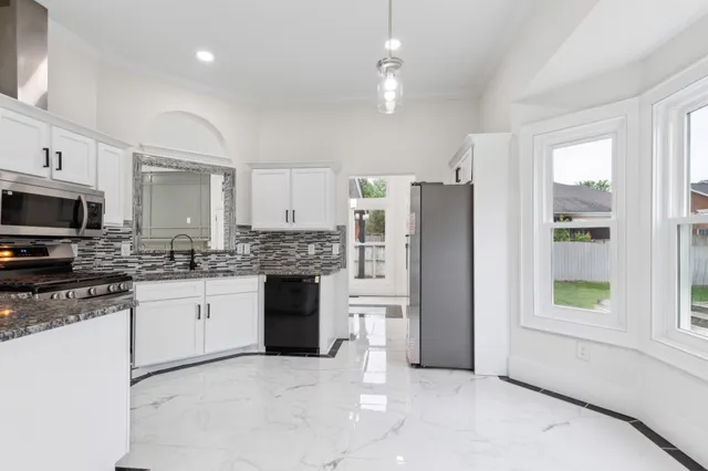 a kitchen with stainless steel appliances granite countertop a refrigerator a stove a sink and a microwave