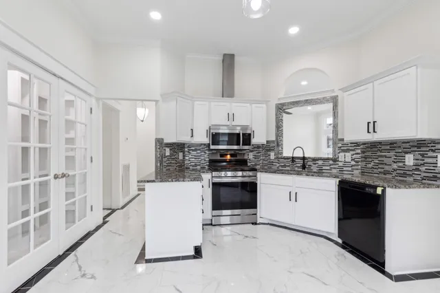 a kitchen with stainless steel appliances granite countertop a stove top oven a sink and a refrigerator