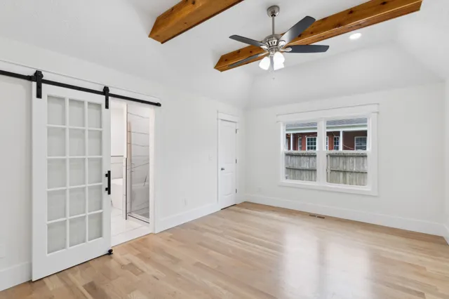 a view of an empty room with a window and wooden floor