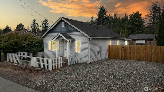 a view of a small house with a small yard and wooden fence