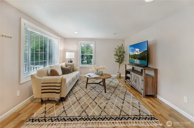 a living room with furniture a flat screen tv and floor to ceiling window