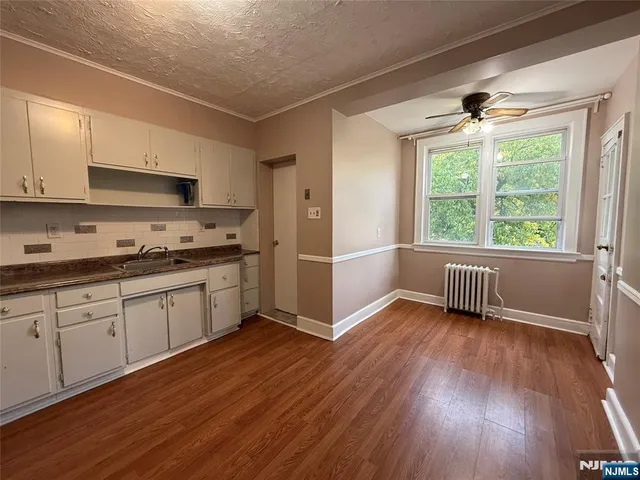 a kitchen with wooden floors and white cabinets