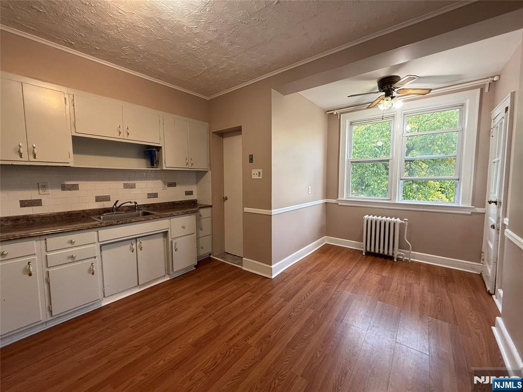 84 9th Street, Unit 1 Wood-Ridge, NJ 07075 - Photo 11 of 22 a kitchen with wooden floors and white cabinets