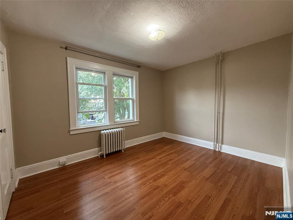 84 9th Street, Unit 1 Wood-Ridge, NJ 07075 - Photo 14 of 22 an empty room with wooden floor and windows