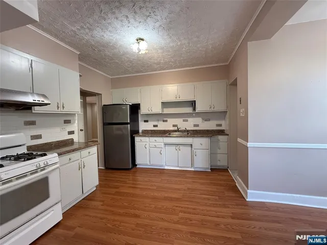 a kitchen with granite countertop a refrigerator stove top oven and cabinets